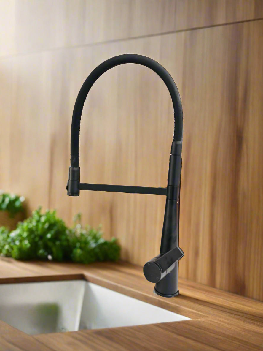 A modern kitchen sink mixer tap with a matte black finish, featuring a 360° swivel spout and a detachable handpiece, installed in a kitchen setting.