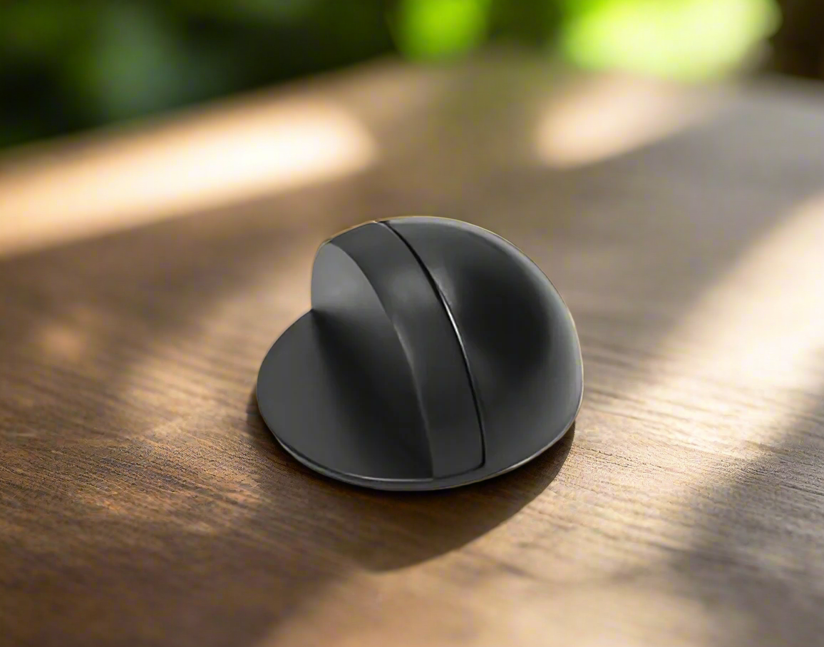A matte black half moon door stopper on a wooden floor.