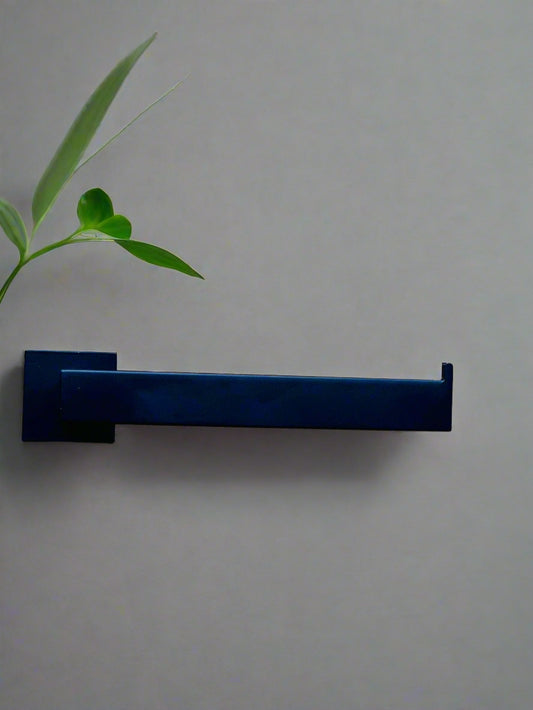 A black stainless steel hand towel holder rack mounted on a wall, with a green plant leaf in the upper left corner.