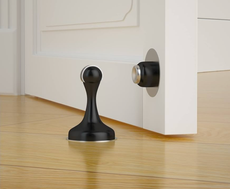 Black door stopper on a wooden floor with a white cabinet