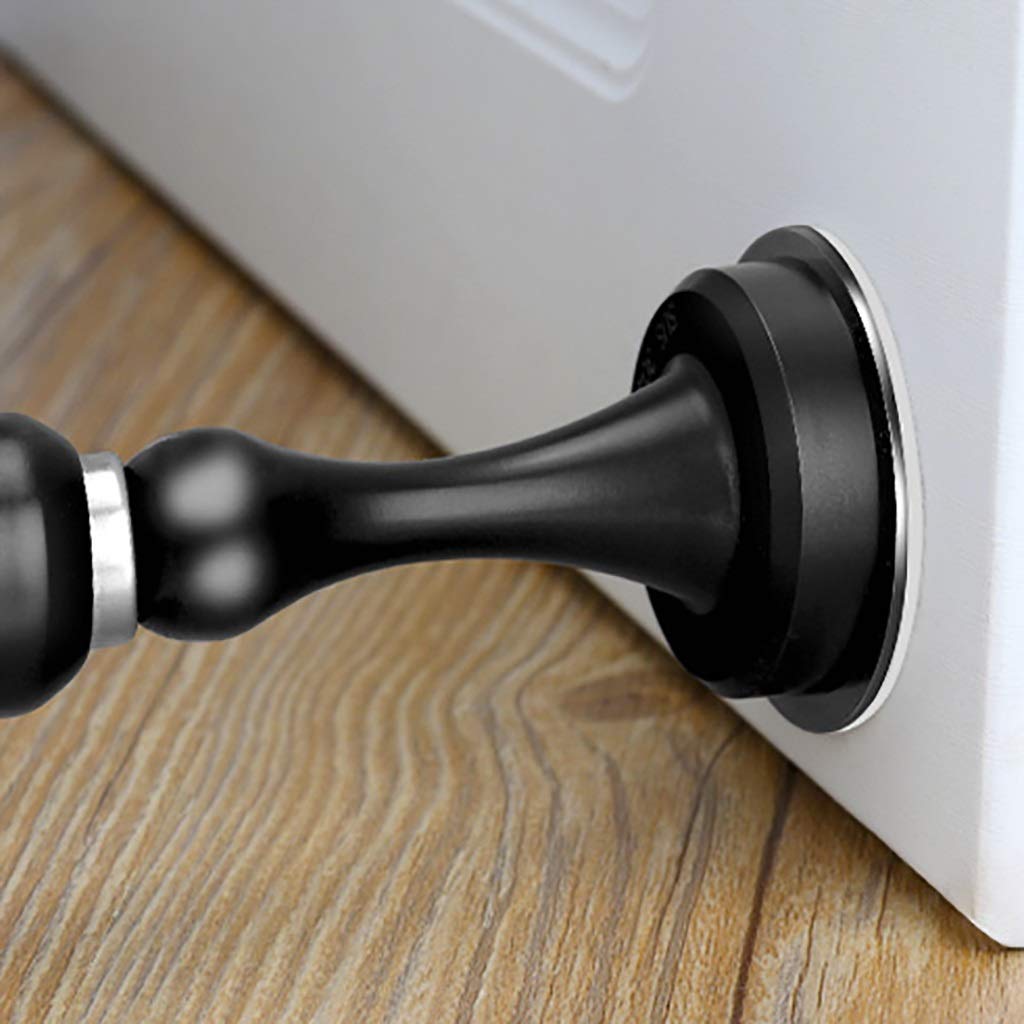 Black door stopper attached to a white door on a wooden floor.