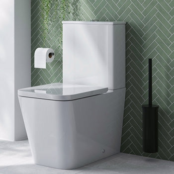 White toilet against a green tiled wall with a roll of toilet paper on the tank.