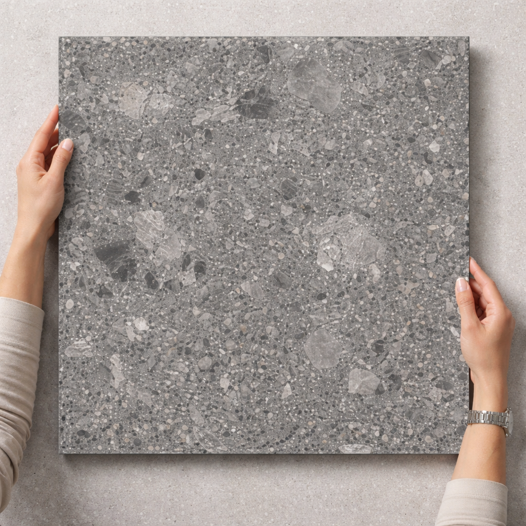 Person holding a gray stone tile against a light gray background