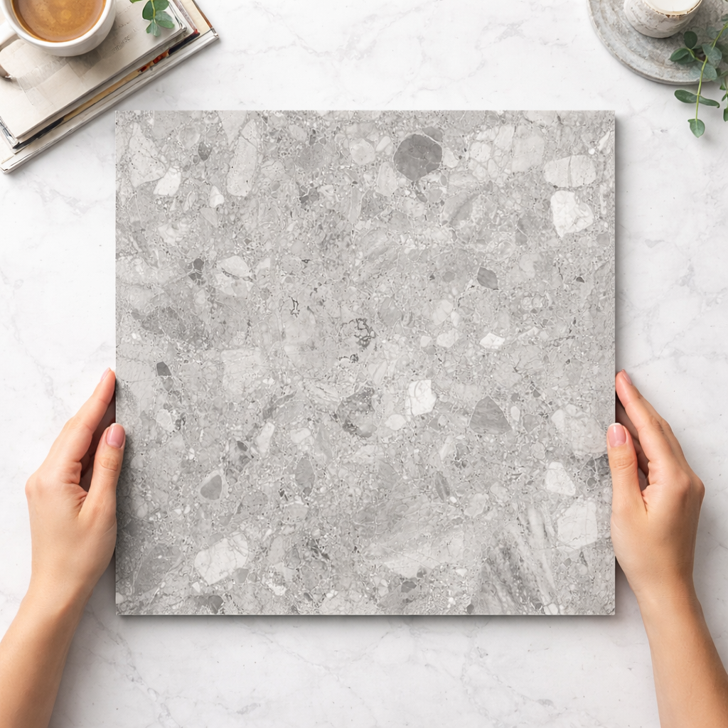 Person holding a gray marble-patterned cutting board on a light gray surface.