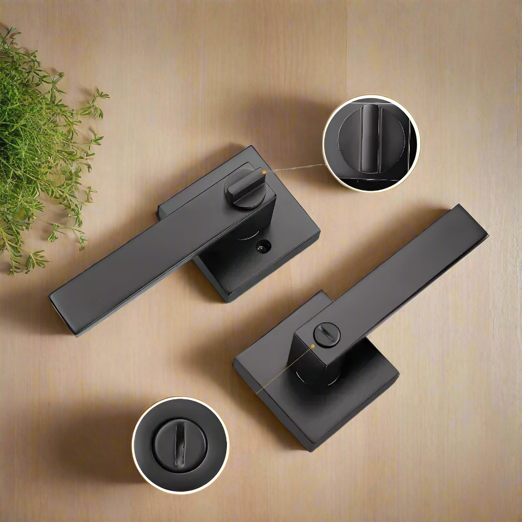 A black door handle with a lever and a keyhole, displayed on a wooden surface 