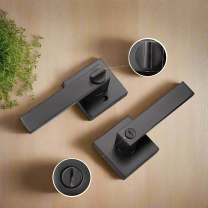 A black door handle with a lever and a keyhole, displayed on a wooden surface 