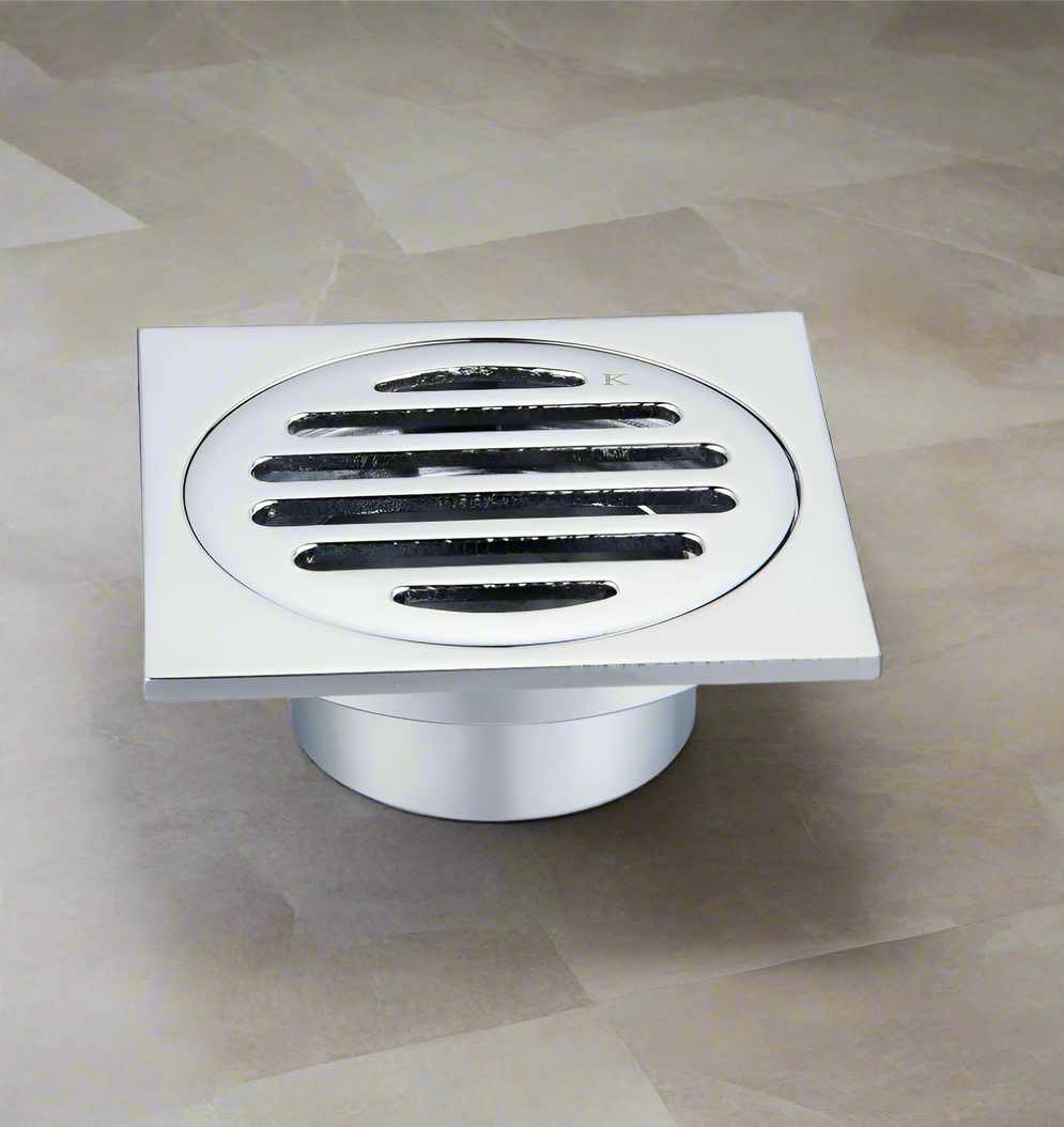 A black square floor waste drain grate installed on a tiled bathroom floor.