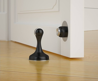 Black door stopper on a wooden floor with a white cabinet 