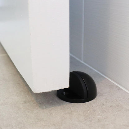 Black door stopper on a carpeted floor next to a white door