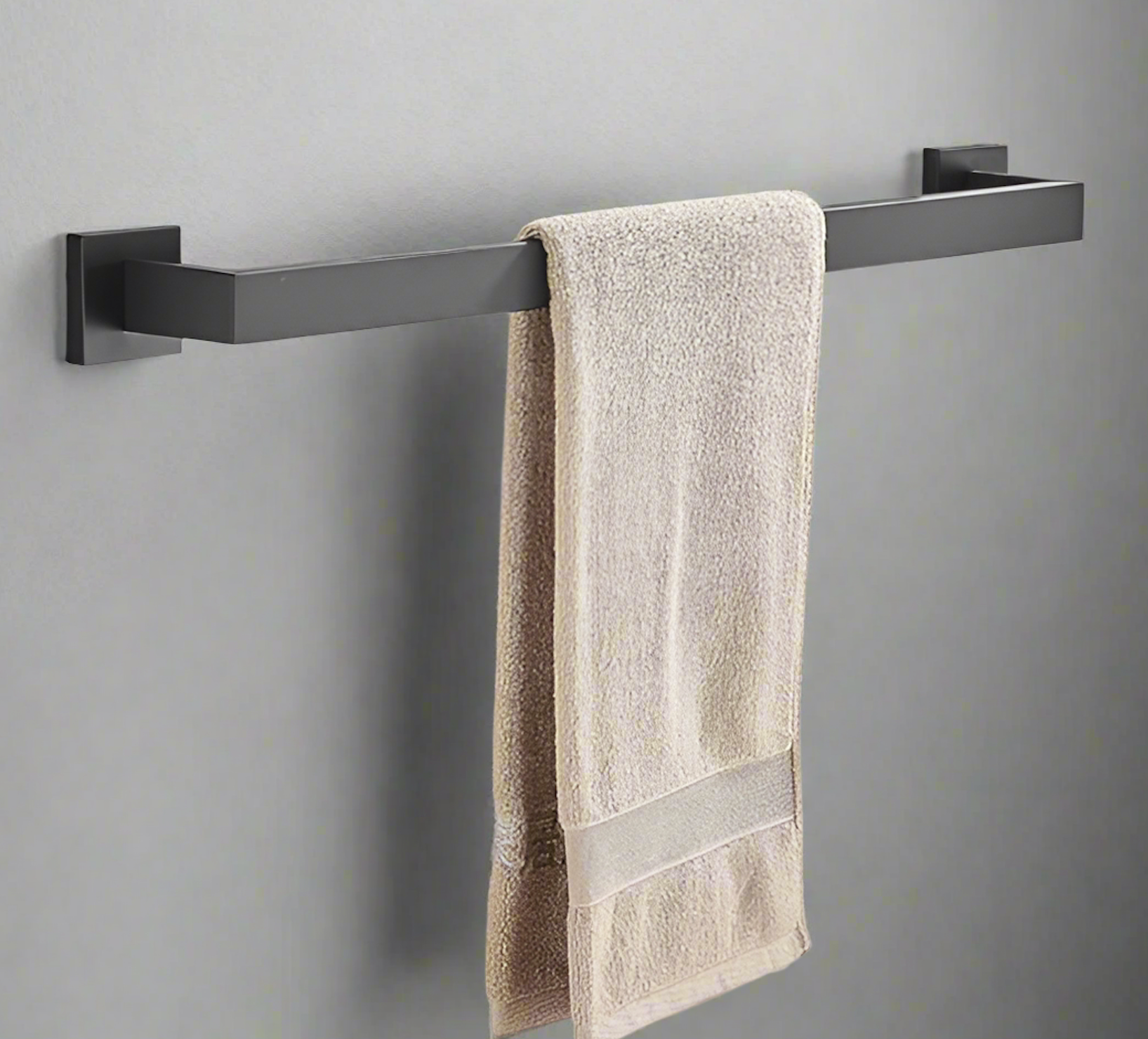Black towel rack with a beige towel on a gray wall