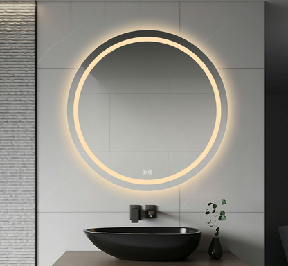 A round frameless LED mirror with anti-fog feature, illuminated with warm white light, mounted above a bathroom sink.