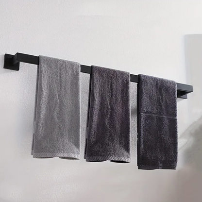 Three gray towels hanging on a black towel rack against a white wall.