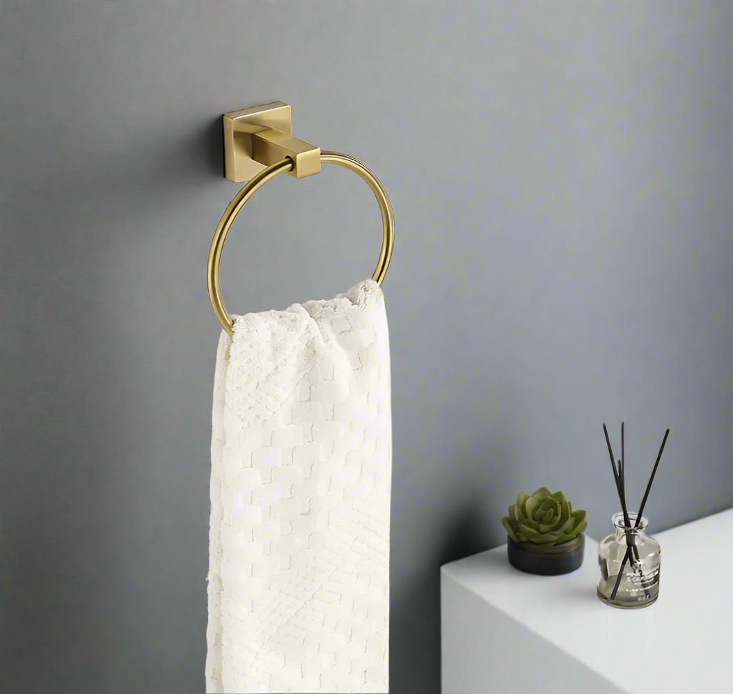 A gold  color stainless steel hand towel holder ring mounted on a grey wall.