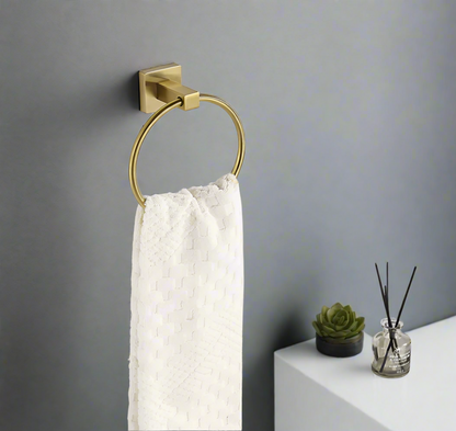 A gold  color stainless steel hand towel holder ring mounted on a grey wall.